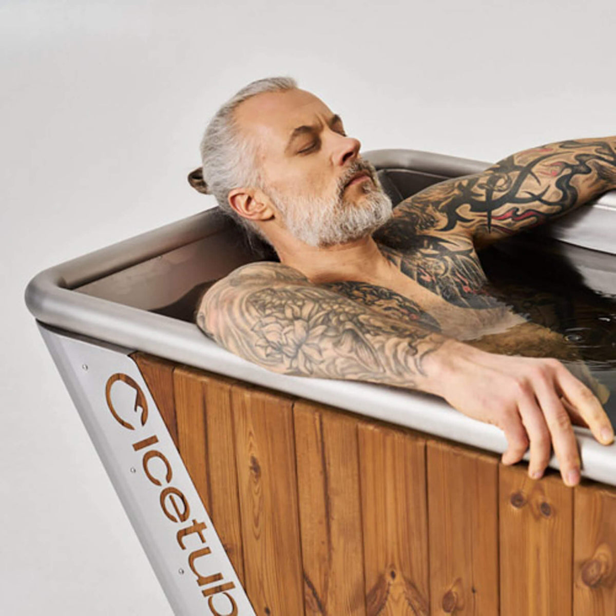 Man with tattoos relaxing in a wooden bathtub Icetubs