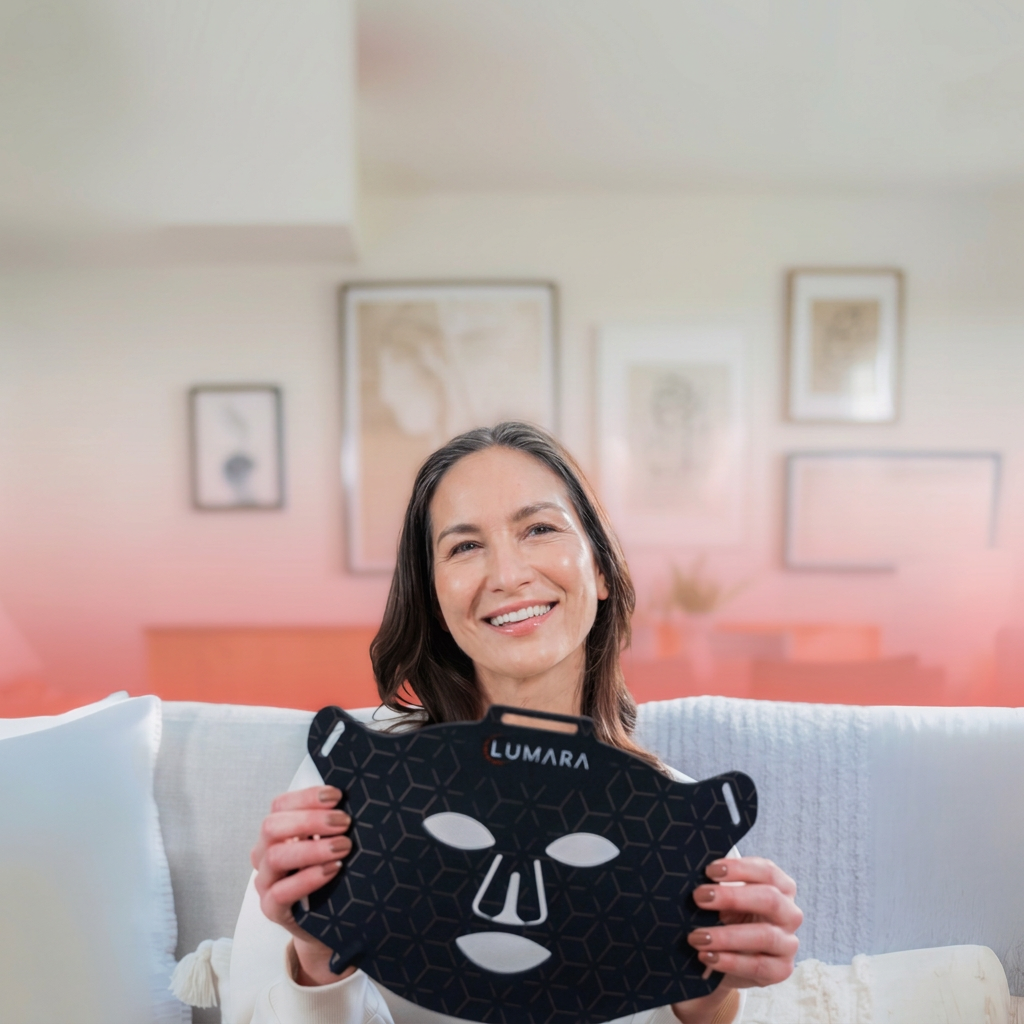 Woman sitting on a couch holding a Lumara VISO LED face mask